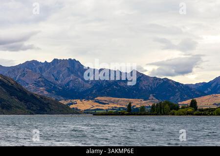 Lac Wanaka, un après-midi nuageux d'été avec une chaîne de montagnes et la ville de Wanaka sur le rivage. Île du Sud, Nouvelle-Zélande Banque D'Images