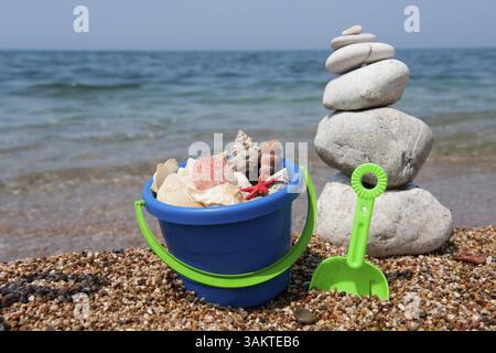 Coquillages sur la plage de galets empilés avec godet coloré Banque D'Images