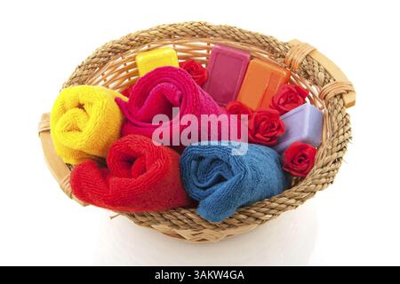 Serviettes colorées savon et roses dans le panier de canne Banque D'Images