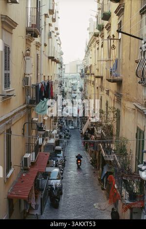 Rue étroite à Naples avec de vieilles maisons, Italie. Moto conduisant le long de la ruelle. Linge accroché sur les balcons Banque D'Images