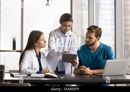 Jeune femme médecin mentor enseigner les stagiaires expliquer le diagnostic à l'aide de comprimés Banque D'Images