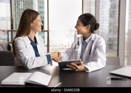 Deux femmes heureuses et diverses professionnelles médicales se serrent la main après avoir fait affaire Banque D'Images