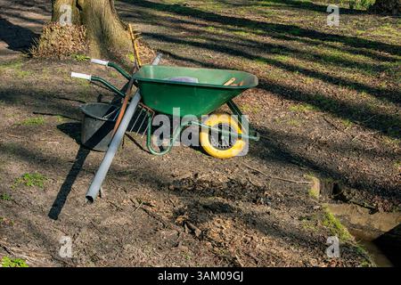 brouette verte avec pneu avant jaune se dresse à l'extérieur dans la forêt Banque D'Images