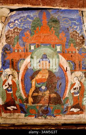 Murale décolorée d'un Bouddha assis flanquée par des préposés dans la cour du monastère de Hemis, un site bouddhiste tibétain majeur du Ladakh. Banque D'Images