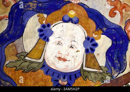 Détail mural d'un musicien céleste ou d'une figurine accompagnatrice avec coiffure élaborée et ornements floraux, monastère Thiksey, Ladakh. Banque D'Images