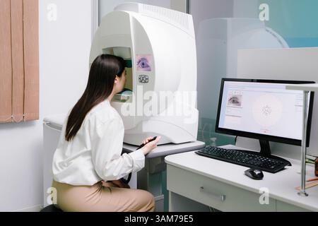 Test oculaire périmétrique pour le signe précoce du glaucome chez une patiente de clinique ophtalmologique. Test de champ visuel périmétrique pour mesurer toutes les zones de la vue Banque D'Images