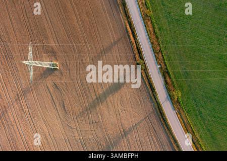 Drone tiré avec pylône électrique sur des champs agricoles au lever du soleil. Paysage rural avec champs agricoles et route de campagne Banque D'Images