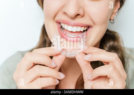 Gros plan de la femme souriante insérant un aligneur transparent clair dans la bouche, le redressement des dents et le sourire parfait de beauté Banque D'Images