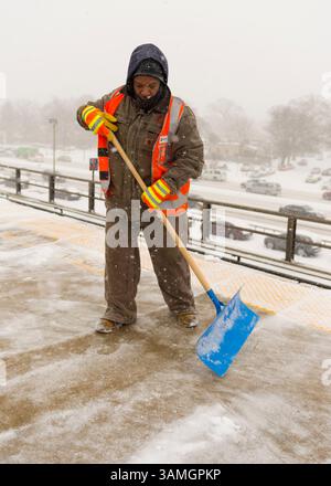 21 janvier 2014 - Merrick, New York, États-Unis - les membres du personnel de maintenance of Way (MOW) de la Metropolitan transit Authority (MTA) pelletent la neige qui tombe lourdement sur la plate-forme surélevée venteuse de la gare ferroviaire de Merrick. La Metropolitan transit Authority a ajouté des trains supplémentaires l'après-midi à long Island Rail Road. LIRR Tweet à 14 h : « le MTA exhorte les clients à quitter le travail tôt aujourd'hui et à finir de voyager tôt ce soir. Si vous n'avez pas besoin de voyager ce soir, nous vous exhortons à ne pas le faire." Les villes de long Island ont déclaré une urgence de neige, avec jusqu'à 10 pouces de neige attendus. (Crédit image : © Ann Parry/ZUMA Wire/ZUMAPRES Banque D'Images