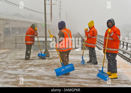 21 janvier 2014 - Merrick, New York, États-Unis - faisant une brève pause pour des raisons de sécurité alors qu'un train se précipite dans la gare ferroviaire LIRR de Merrick, les membres du personnel de maintenance of Way (MOW) pellent la neige alors qu'elle tombe lourdement sur la plate-forme surélevée venteuse. (Crédit image : © Ann Parry/ZUMA Wire/ZUMAPRESS.com) Banque D'Images