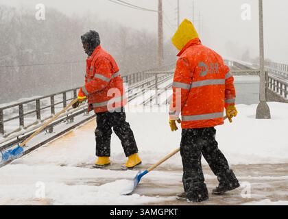 21 janvier 2014 - Merrick, New York, États-Unis - les membres du personnel de maintenance of Way (MOW) de la Metropolitan transit Authority (MTA) pelletent la neige qui tombe lourdement sur la plate-forme surélevée venteuse de la gare ferroviaire de Merrick. La Metropolitan transit Authority a ajouté des trains supplémentaires l'après-midi à long Island Rail Road. LIRR Tweet à 14 h : « le MTA exhorte les clients à quitter le travail tôt aujourd'hui et à finir de voyager tôt ce soir. Si vous n'avez pas besoin de voyager ce soir, nous vous exhortons à ne pas le faire." Les villes de long Island ont déclaré une urgence de neige, avec jusqu'à 10 pouces de neige attendus. (Crédit image : © Ann Parry/ZUMA Wire/ZUMAPRES Banque D'Images