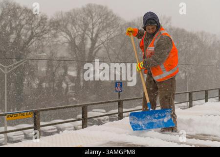21 janvier 2014 - Merrick, New York, États-Unis - les membres du personnel de maintenance of Way (MOW) de la Metropolitan transit Authority (MTA) pelletent la neige qui tombe lourdement sur la plate-forme surélevée venteuse de la gare ferroviaire de Merrick. La Metropolitan transit Authority a ajouté des trains supplémentaires l'après-midi à long Island Rail Road. LIRR Tweet à 14 h : « le MTA exhorte les clients à quitter le travail tôt aujourd'hui et à finir de voyager tôt ce soir. Si vous n'avez pas besoin de voyager ce soir, nous vous exhortons à ne pas le faire." Les villes de long Island ont déclaré une urgence de neige, avec jusqu'à 10 pouces de neige attendus. (Crédit image : © Ann Parry/ZUMA Wire/ZUMAPRES Banque D'Images