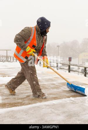 21 janvier 2014 - Merrick, New York, États-Unis - les membres du personnel de maintenance of Way (MOW) de la Metropolitan transit Authority (MTA) pelletent la neige qui tombe lourdement sur la plate-forme surélevée venteuse de la gare ferroviaire de Merrick. La Metropolitan transit Authority a ajouté des trains supplémentaires l'après-midi à long Island Rail Road. LIRR Tweet à 14 h : « le MTA exhorte les clients à quitter le travail tôt aujourd'hui et à finir de voyager tôt ce soir. Si vous n'avez pas besoin de voyager ce soir, nous vous exhortons à ne pas le faire." Les villes de long Island ont déclaré une urgence de neige, avec jusqu'à 10 pouces de neige attendus. (Crédit image : © Ann Parry/ZUMA Wire/ZUMAPRES Banque D'Images