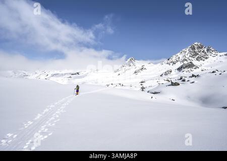 Randonneur de ski montant à travers un paysage de montagne enneigé pittoresque avec des sommets, ascension au sommet de Kesch Pitschen, Buendner haute route ski Banque D'Images
