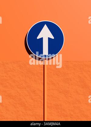 Le panneau de signalisation obligatoire indiquant le seul sens de déplacement autorisé est droit vers l'avant, monté sur un poteau contre un mur orange. Rendu 3D. Banque D'Images