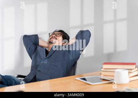 Homme d'affaires dans le bureau se relaxant dans la chaise. Lorsque vous investissez en vous-même et que cela paie. Plan d'un beau jeune homme d'affaires se relaxant avec ses pieds vers le haut o Banque D'Images