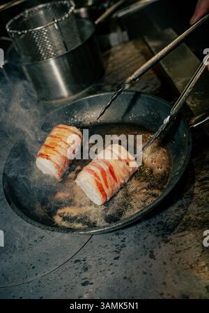 Une personne fait cuire du bacon dans une casserole. Le bacon a la forme d'une saucisse et est cuit des deux côtés Banque D'Images