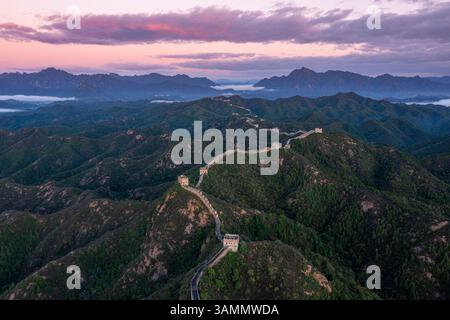 Vue aérienne de la majestueuse Grande Muraille de Jinshanling au milieu des montagnes pittoresques et des nuages au coucher du soleil, Chengde, Chine. Banque D'Images