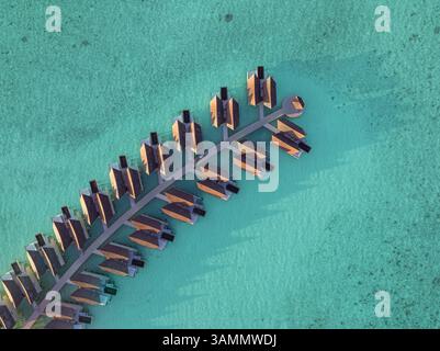Vue aérienne des bungalows sur l'eau entourés d'eau turquoise et de paysages tropicaux luxuriants, île de Kuredhivaru, atoll de Noonu, Maldives. Banque D'Images