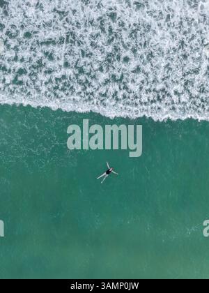 Vue aérienne d'une plage sereine avec des vagues et une personne nageant dans le golfe du Mexique, Siesta Key, États-Unis. Banque D'Images