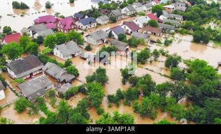 Quartier inondé de maisons et d'arbres submergés. Vue aérienne d'une zone résidentielle inondée avec des maisons, des arbres et des rues submergés dans l'eau brune Banque D'Images