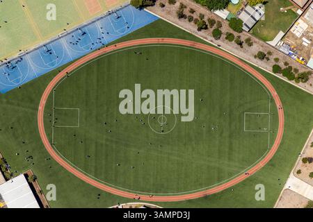 Vue aérienne du terrain de sport et de la piste de course entourés de bâtiments et d'arbres, Melton West, Australie. Banque D'Images