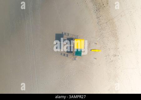 Vue aérienne d'une chaise jaune de sauveteur et d'une planche de sauvetage sur une plage au lever du soleil avec de longues ombres projetées depuis les chaises, Durban, Kwa Zulu Natal, Afrique du Sud. Banque D'Images