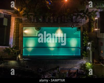 Vue aérienne de nuit de la piscine illuminée et de la natation de l'homme, Tagbilaran, Philippines. Banque D'Images