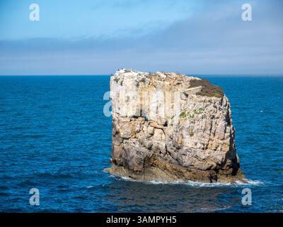 Île rocheuse isolée entourée par les eaux de l'océan bleu profond le jour ensoleillé au Portugal Banque D'Images