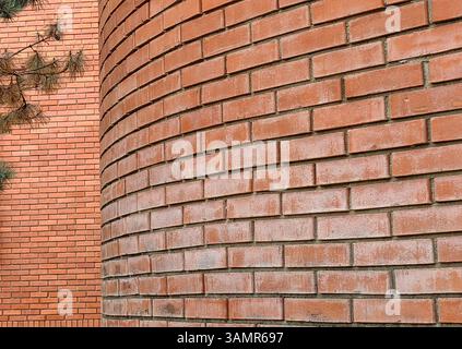 au coin de la rue. mur de briques , couches de briques différentes. teintes. structure de lignes. ambiance rétro. branches d'arbre vertes. Banque D'Images