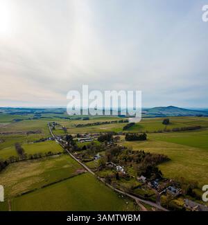 Vue aérienne du village paisible niché parmi les collines et les prairies, Chesters, Hawick, Écosse. Banque D'Images