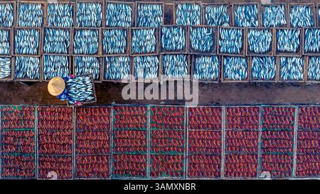 Vue aérienne du poisson séchant sur des casiers avec des ouvriers en chapeaux de paille, long Hai, Vietnam. Banque D'Images