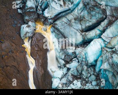 Vue aérienne du glacier solheimajokull avec des formations de glace majestueuses et une cascade sereine, Oraefi, Islanda. Banque D'Images