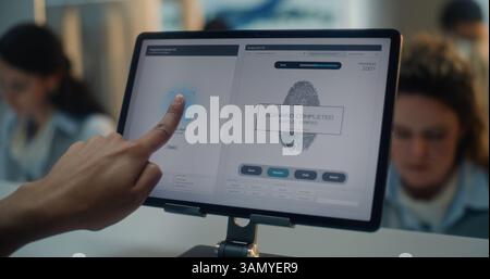 Comptoir d'enregistrement à l'aéroport : gros plan d'un touriste indien mettant le doigt sur l'écran tactile pour la numérisation d'empreintes digitales. Programme de tablette numérique pour vérifier les données biométriques des passagers pour le vol. Terminal de l'aéroport. Banque D'Images