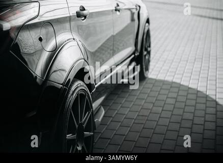 Culture de réglage de la voiture - côté du VUS sportif. Image de mise au point sélective de la partie arrière d'une voiture noire abaissée avec jantes noires. Banque D'Images