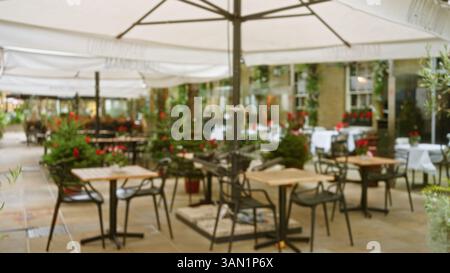 Café en plein air floue à londres avec des tables et des chaises placées sous des parasols dans un cadre hivernal ou automnal riche en bokeh, évoquant une atmosphère festive et chaleureuse Banque D'Images