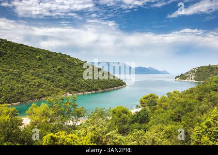 La côte maritime du sud de la Dalmatie en Croatie, Europe. Sérénité côtière : des collines verdoyantes rencontrent des eaux cristallines sous un ciel lumineux, un paysage paisible Banque D'Images
