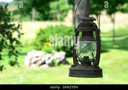 Ancienne lanterne rouillée au kérosène suspendue à l'extérieur dans le fond de cour arrière de la maison. Lampe à huile vintage suspendue à l'extérieur. Banque D'Images
