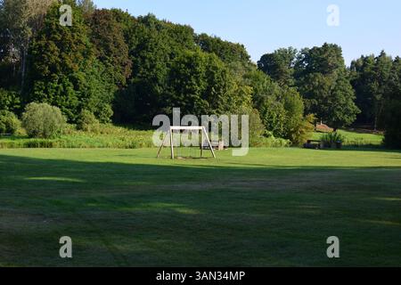 Camping vert avec balançoires en bois et bancs en campagne. Lieu de pique-nique barbecue grillant dans la zone rurale. Banque D'Images