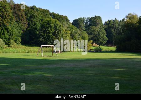 Camping vert avec balançoires en bois et bancs en campagne. Lieu de pique-nique barbecue grillant dans la zone rurale. Banque D'Images