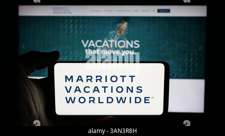 Stuttgart, Allemagne - 12-02-2024 : personne tenant un téléphone portable avec le logo de la société américaine Marriott Vacations Worldwide Corporation sur l'écran Banque D'Images