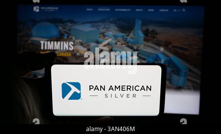 Stuttgart, Allemagne - 12-03-2024 : personne tenant un téléphone portable avec le logo de la société minière Pan American Silver Corporation sur l'écran en face de la page Web. Banque D'Images