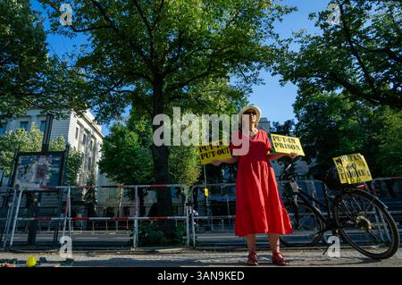 Une femme proteste devant l'ambassade de Russie à Berlin, tenant des pancartes jaunes avec des messages anti-Poutine exigeant justice et résistance contre la guerre Banque D'Images