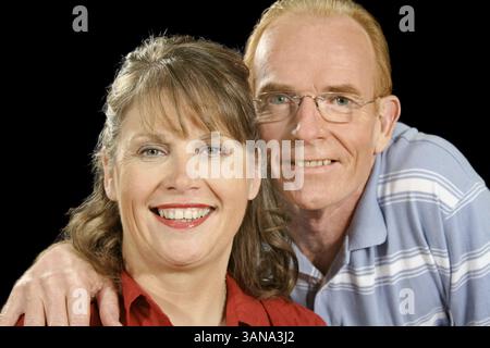 Heureux couple d'âge moyen souriant et regardant la caméra Banque D'Images
