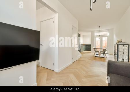 Un intérieur moderne lumineux et spacieux présente un décor minimaliste avec parquet et mobilier contemporain, créant une atmosphère chaleureuse et accueillante. Banque D'Images