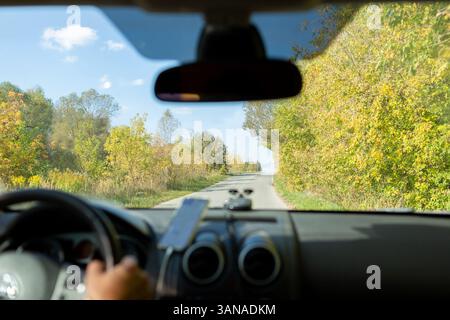 Un homme dans une voiture vérifie la route à l'aide d'un navigateur à partir d'un téléphone portable Banque D'Images