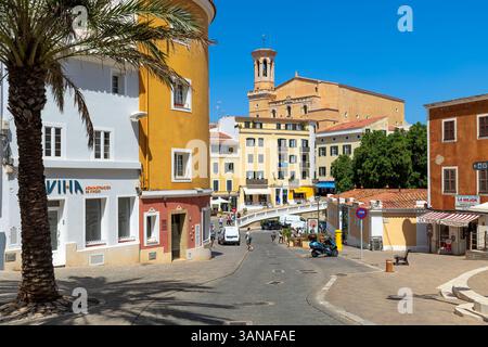 Une scène de rue avec des bâtiments colorés, un palmier, et une tour d'église sous le ciel bleu à Mahon, îles Baléares, Espagne. Banque D'Images
