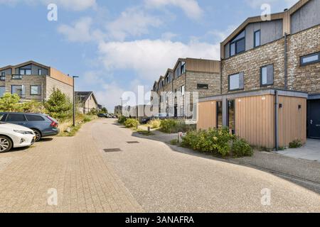 Cette image montre une rue résidentielle moderne avec des maisons contemporaines le long de trottoirs bien entretenus et de verdure, capturant la vie de banlieue. Banque D'Images
