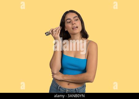 Modèle utilisant un applicateur de maquillage électronique, présentant la routine de beauté moderne Banque D'Images