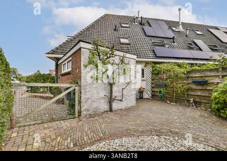 Une maison résidentielle contemporaine avec panneaux solaires sur le toit, entourée de verdure et d'un jardin bien entretenu. Banque D'Images